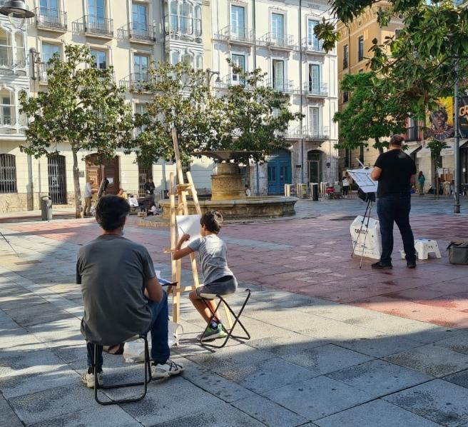 Niño acompañado pintando en la calle